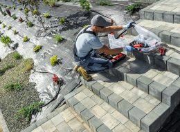 Caucasian Professional Landscaping Worker in His 40s Building Rockery Garden Drip Irrigation System. Modern Backyard Watering Systems.